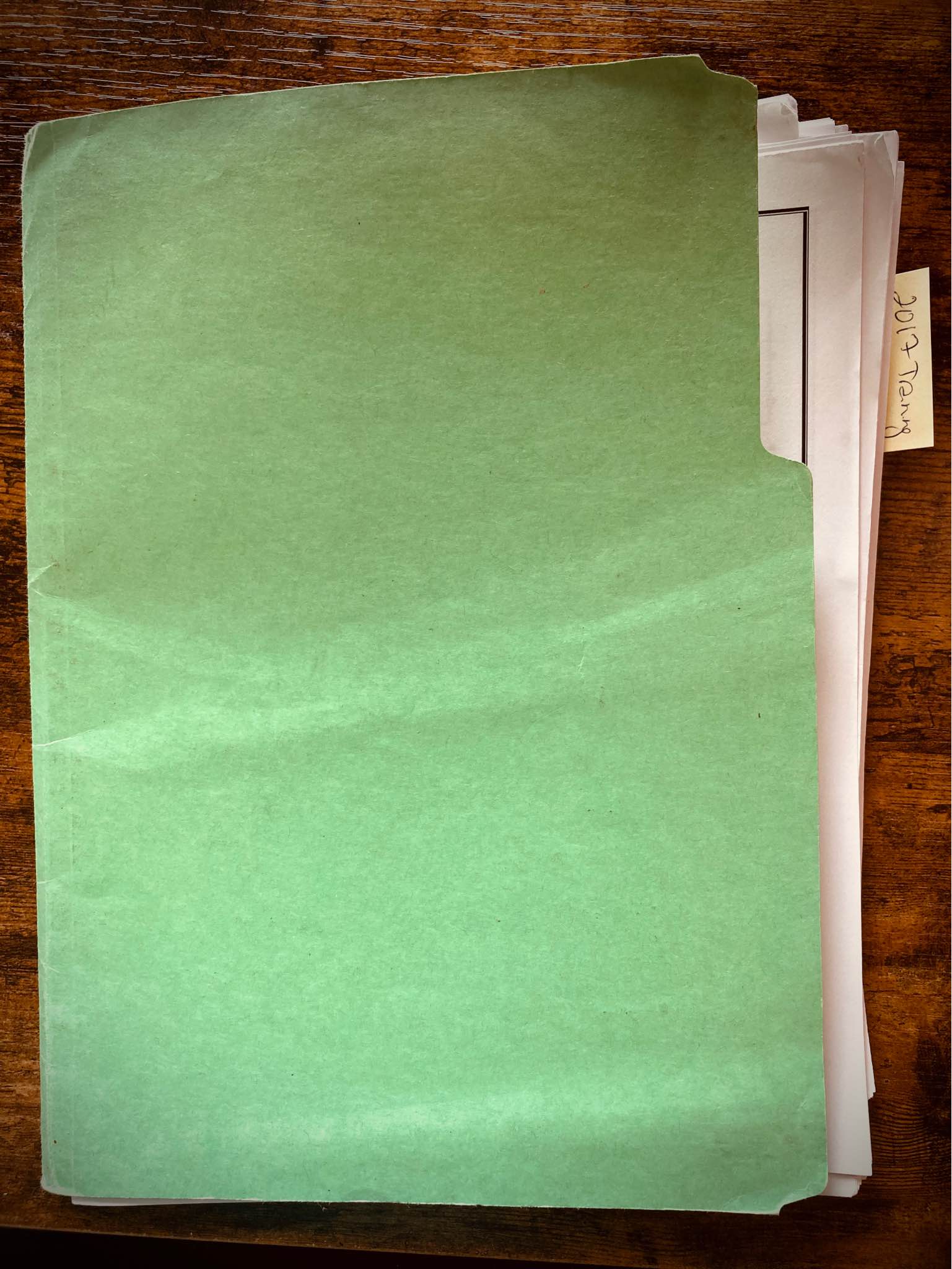 Photo of a green folder on a wooden desktop. The folder contains lots of dog-eared sheets of paper, with a post-it note sticking off the side that says "2017 Training."