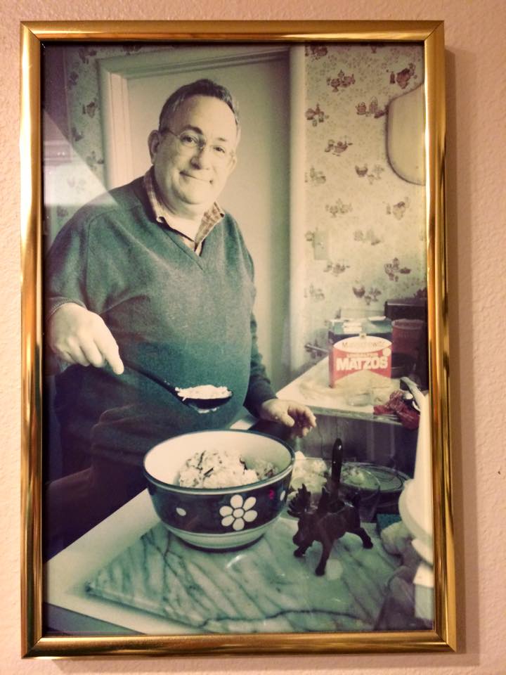 A faded color photo of an older man cooking in a sunny kitchen